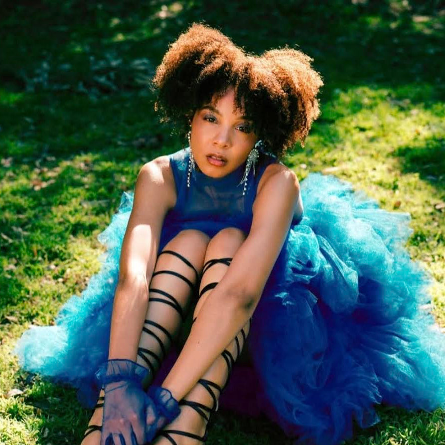 Woman in a blue dress sitting on grass